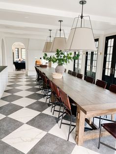 a dining room table with chairs and lamps hanging from the chandelier over it