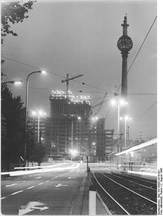 a black and white photo of a train track at night with buildings in the background