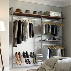 an organized closet with clothes and shoes hanging on the wall, next to a bed