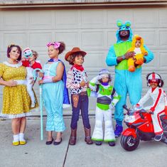 a group of people in costumes standing next to each other on the sidewalk near a garage door