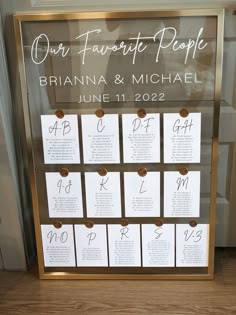 a wedding seating chart is displayed in a glass case with gold trim around the edges