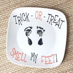 a plate with hand and foot prints on it that says trick or treat smell my feet