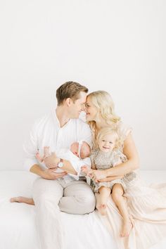 a man, woman and baby are sitting on a bed with their arms around each other