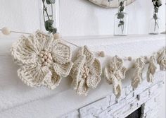 crocheted flowers are hanging on the mantle in front of a mirror and fireplace