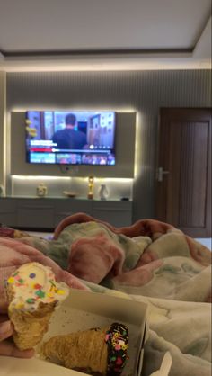 an ice cream cone with sprinkles is in someone's hand while watching tv