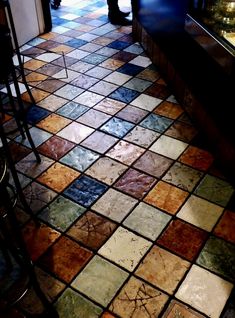 a tiled floor with bars and stools in the background