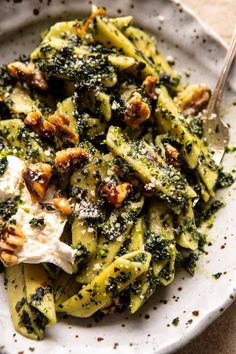 a white plate topped with pasta covered in pesto