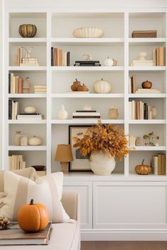 a living room filled with lots of white bookshelves and pumpkins on top of them