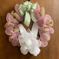 a wreath made out of burlocks and mesh with a bunny on it hanging on a door