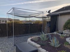 a backyard area with rocks, plants and a fence