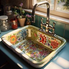 a kitchen sink with colorful flowers painted on the front and sides, next to a window