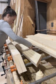 a woman working on some wood in a shop