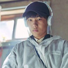 a young man wearing headphones and a baseball cap