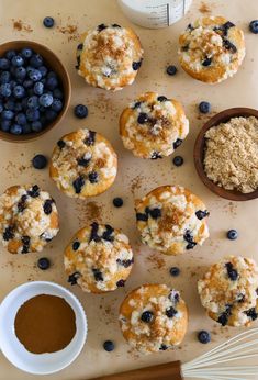 blueberry muffins with powdered sugar and bowls of blueberries next to them