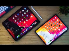 two tablets sitting next to each other on top of a wooden table with a keyboard and mouse