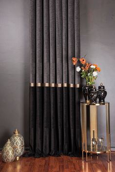 a vase with flowers sitting on top of a table next to a black and gold curtain