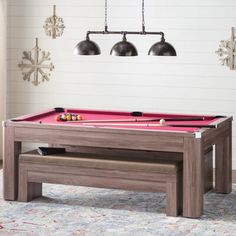 a pool table in a living room with two lamps on the wall and a bench underneath it