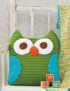 a crocheted owl pillow sitting on top of a white chair next to a wooden block