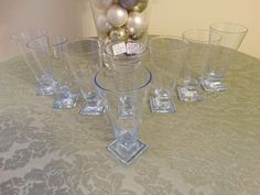 a table topped with lots of glass cups and vases filled with christmas ornaments on top of a table