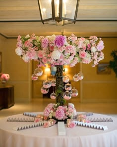 a table topped with lots of pink flowers next to a tall vase filled with bubbles