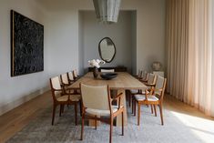 a dining room table with chairs and a large painting on the wall in the background