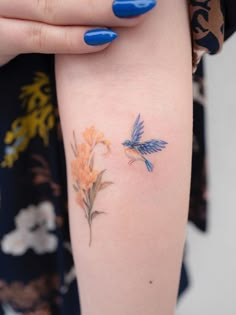 a woman's arm with flowers on it and a blue nail polish varing