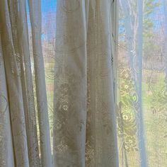 an open window with white curtains and green grass in the background