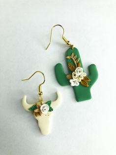 the earrings are decorated with flowers and an animal's head on them, sitting next to each other