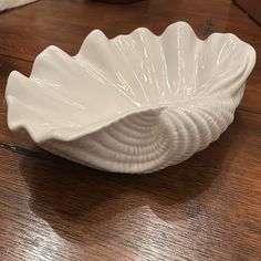 a white shell shaped bowl sitting on top of a wooden table