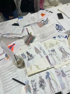 a table covered with drawings and paper on top of it