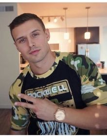 a man in camo shirt pointing at the camera with his hand on his hip