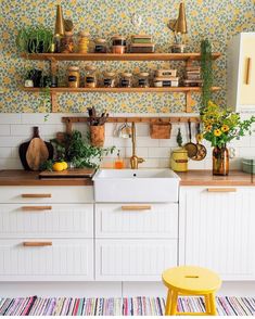 a kitchen filled with lots of white cabinets and counter top next to a yellow stool