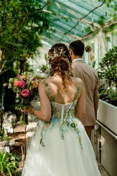 a bride and groom walking through a greenhouse