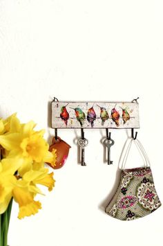 a wall mounted coat rack with keys and flowers in front of it on a white wall