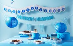 a blue table topped with lots of boxes and paper lantern lights next to a sign that reads raman mubarak