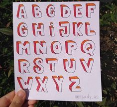 a hand holding up a piece of paper with letters and numbers drawn on it in different colors