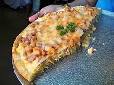 a person holding up a large slice of pizza on a metal platter with cheese and other toppings