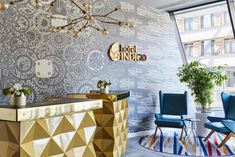 a hotel lobby with gold and blue chairs, a large wall mural and a bar