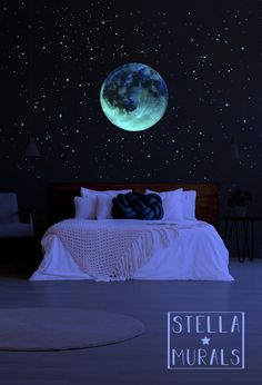 a bed with white sheets and pillows in front of a night sky wall decal