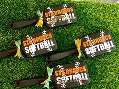 four baseball bat shaped bottle openers sitting on top of green grass with the words st george's softball written on them