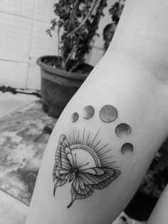 a black and white photo of a woman's arm with a sun tattoo on it