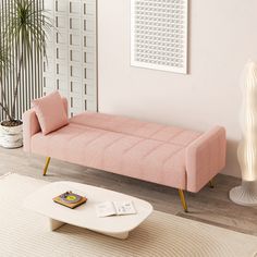 a living room with a pink couch and white coffee table in front of the wall