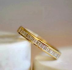 two gold wedding bands sitting on top of each other in front of a white cake