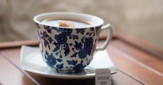 a blue and white coffee cup sitting on top of a saucer next to a tag