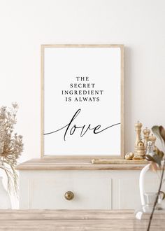 a white dresser with a framed print on it that says, the secret ingredient is always love