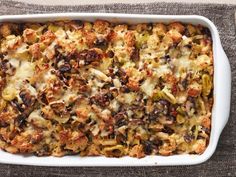 a casserole dish filled with meat and vegetables on top of a gray cloth