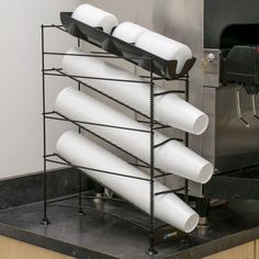 several white cups are stacked on top of each other in front of a metal rack