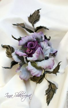 a purple flower is laying on a white cloth