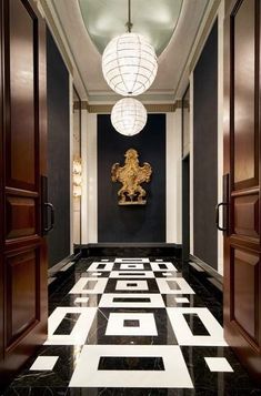 an elegant hallway with black and white marble flooring, chandelier and doors