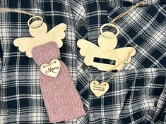 two wooden angel ornaments are hanging on a plaid shirt with a heart shaped ornament